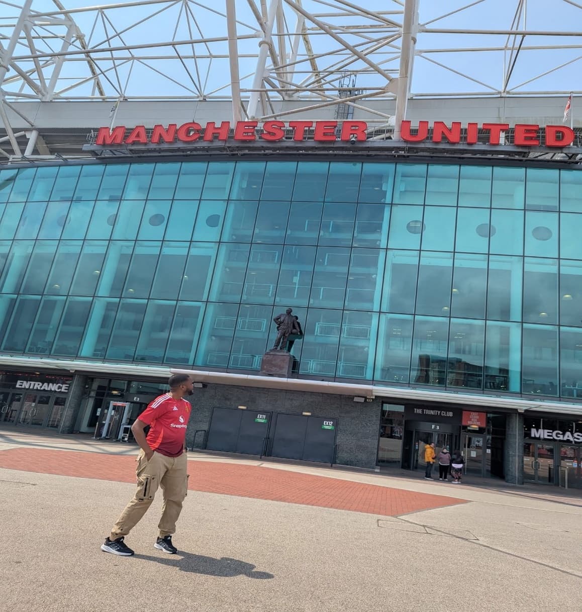 Dr Isaac Kwesi Acquah in a red Manchester United shirt outside Old Trafford.
