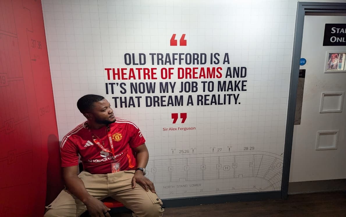 Dr Isaac Kwesi Acquah seated beside a Sir Alex Ferguson quotation inside Old Trafford.